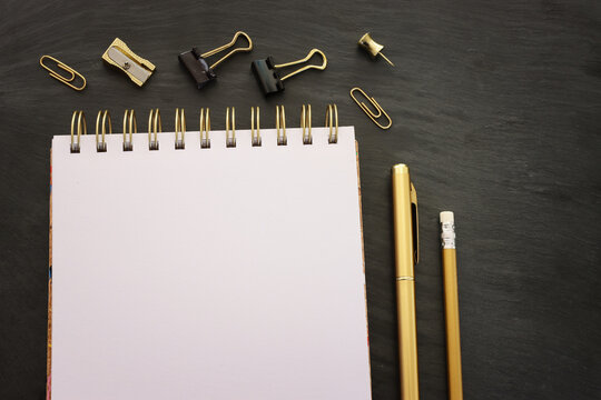 Top view image of black table with notebook and office supplies