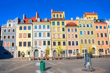 Fototapeta premium Historic Old Town Market Square in Warsaw features row of brightly colored reconstructed townhouses. Cobblestone plaza stretches out in front of the multi-story buildings