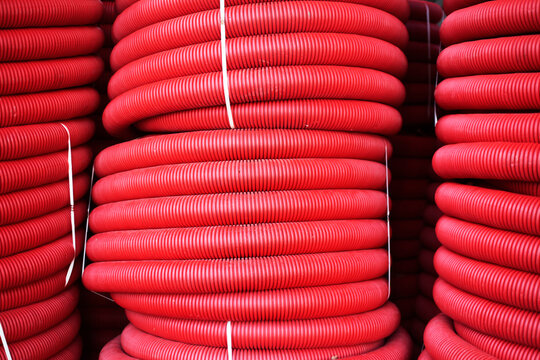 Stacks of red corrugated plastic pipes