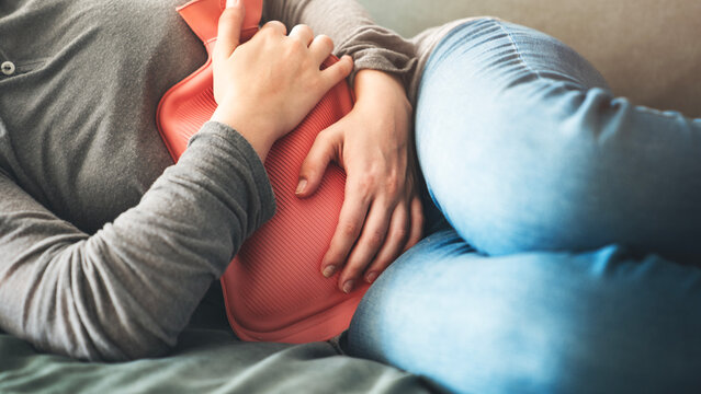 Woman using hot water bottle for stomachache