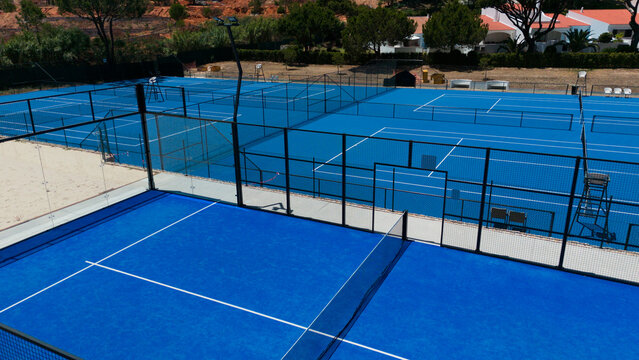 Aerial view of a vibrant padel court with dynamic shadows on a sunny afternoon
