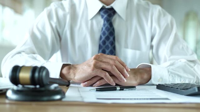 Lawyer working on a laptop at a desk with a gavel, scales of justice, documents and calculator, representing legal services, business law and professional consultation.	