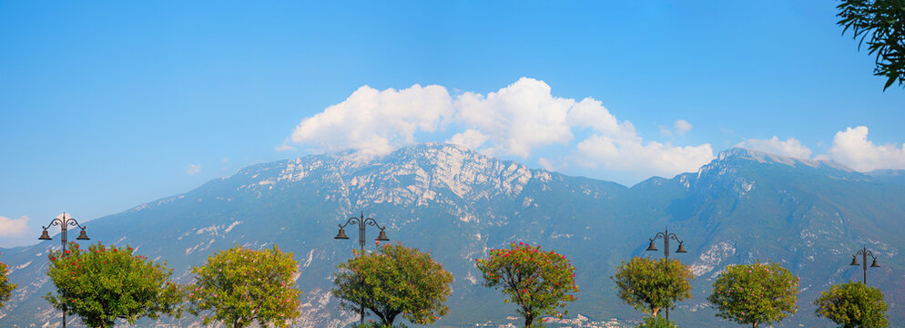 view of Monte Baldo mountain from lakeside Limone, row of blooming oleander trees.