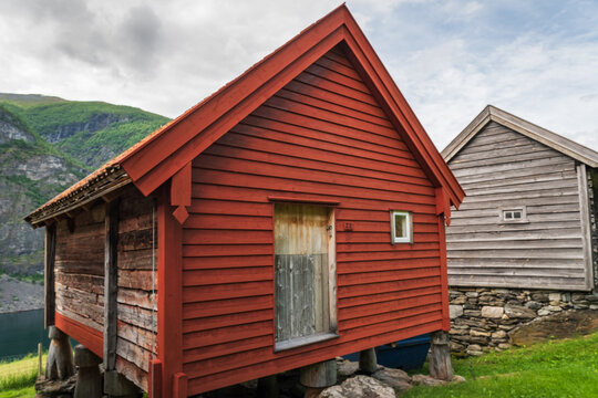 traditional red-painted wooden stabbur storehouse built on stone pillars at the historic Otternes Bygdetun hamlet overlooking Aurlandsfjord, Norway.