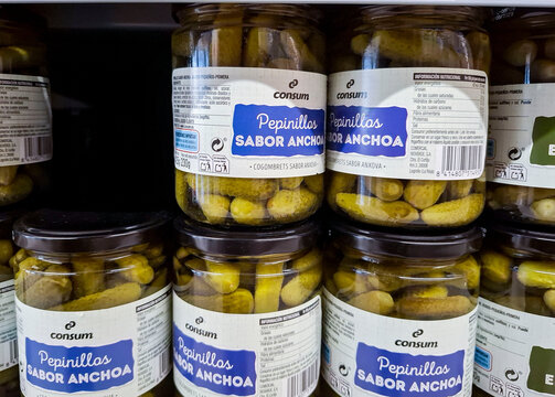 Denia, Spain - October 16, 2025.Glass jars of Consum Pepinillos Sabor Anchoa anchovy flavored pickled gherkins on supermarket shelf in Spain