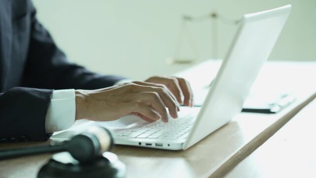 Lawyer working on a laptop with a gavel and scales of justice, representing legal technology, law practice, digital documents, justice, and professional legal services.