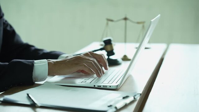 Lawyer working on a laptop with a gavel and scales of justice, representing legal technology, law practice, digital documents, justice, and professional legal services.
