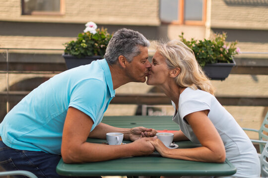 Mature couple kissing across a cafe table