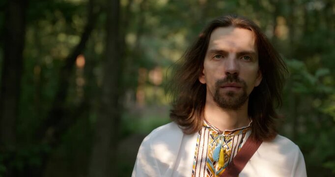 Caucasian man with long hair and Ukrainian traditional folk attire walk wandering on nature. 4K 10-bit