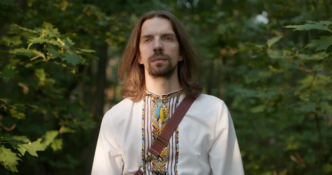 Caucasian man with long hair and Ukrainian traditional folk attire walk wandering on nature. 4K 10-bit