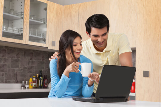 Young couple using laptop in kitchen