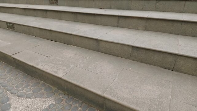 Close up view of weathered outdoor stone steps leading up in an urban setting.