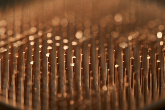 Copper pins arranging in a grid pattern, forming a metallic abstract background with bokeh