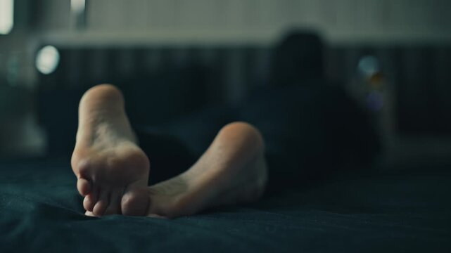 women's feet resting in a dimly lit room with string lights and a dark surface, creating a relaxed atmosphere in a cozy indoor setting with textile and wooden floor elements.