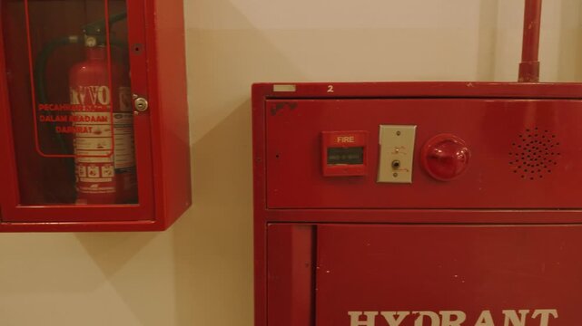 Red fire safety equipment including fire hydrant cabinet and fire extinguisher on wall.