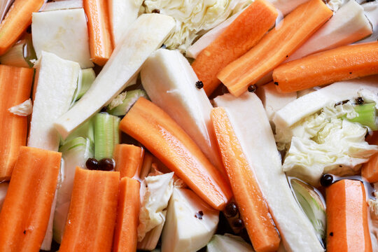 A close-up of chopped vegetables prepared for making broth, including carrots, parsley root, leek, and cabbage.