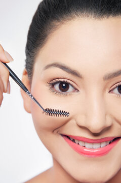 Young woman applying mascara 