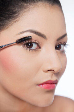 Close-up of pretty young woman applying mascara 