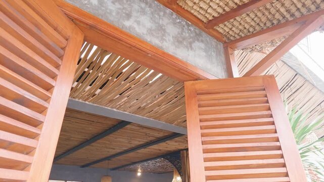 Traditional wooden louvered window shutters and tropical bamboo ceiling architecture.