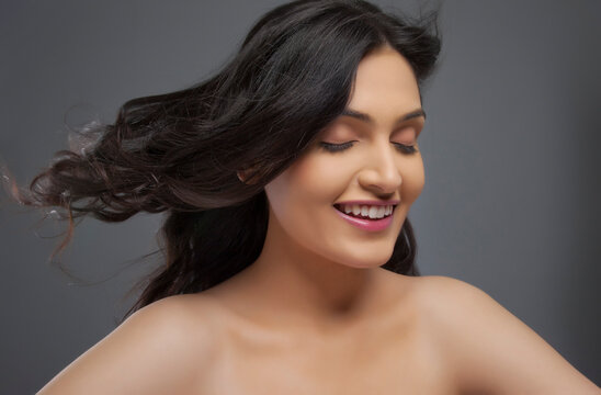 Happy young woman enjoying the breeze over colored background 