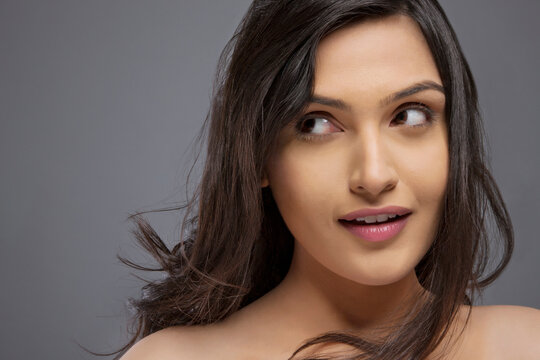 Attractive young female looking sideways over colored background 