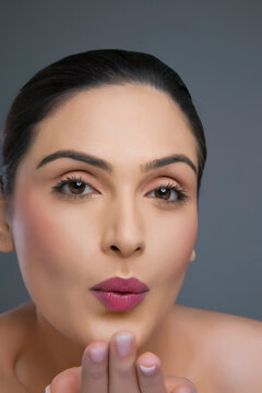 Portrait of an attractive female blowing kiss over colored background 