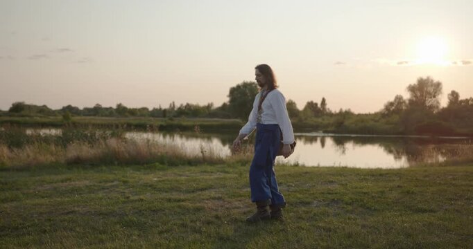 Caucasian man with long hair and Ukrainian traditional folk attire walk wandering on nature. 4K 10-bit