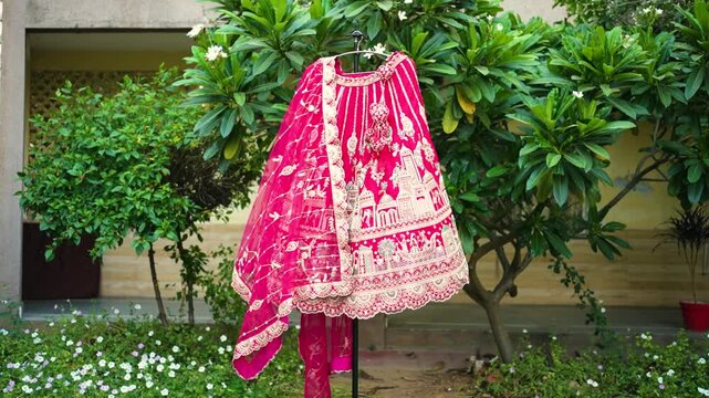 Pink Indian Bridal Lehenga Choli with Intricate Gold Embroidery Hanging Outdoors