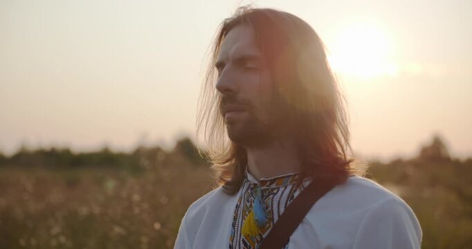 Caucasian man with long hair and Ukrainian traditional folk attire walk wandering on nature. 4K 10-bit