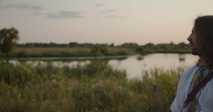 Caucasian man with long hair and Ukrainian traditional folk attire walk wandering on nature. 4K 10-bit