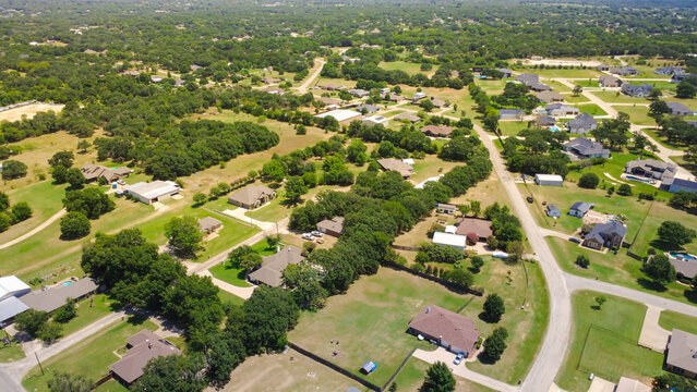Single family homes feature expansive yards, mature tree canopy cover along County Road 602 in suburban Fort Worth. Curving asphalt roads lead through forested acreage, Burleson, TX