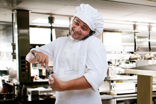 Chef talking on a mobile phone while beating dough 