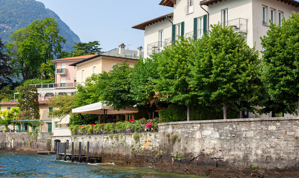 Lake Como Waterfront Buildings with Stone Wall Promenade and Outdoor coastline old Cafe on water in Italy