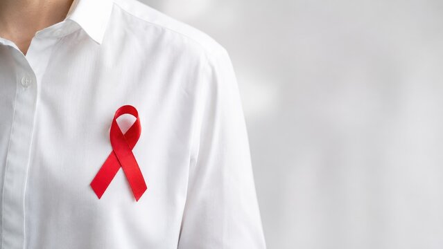 Red awareness ribbon pinned to a white shirt chest, symbolizing HIV/AIDS and health awareness support