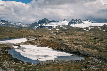 High-altitude tarn with summer ice and snow patches along the Fv55 Sognefjellsvegen mountain pass in Jotunheimen region, Vestland, Norway © Michele