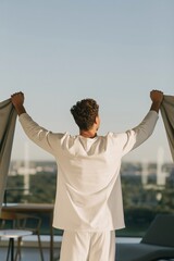 Fototapeta premium Man opening curtains on a balcony in the morning with city view for calm background wallpaper and wellness lifestyle banner design