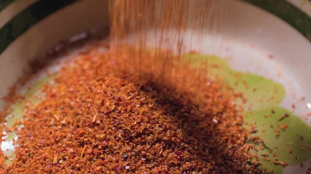 Close up cooking footage showing slow motion of tajin falling onto plate during a homemade chamoy sauce recipe prepared from scratch