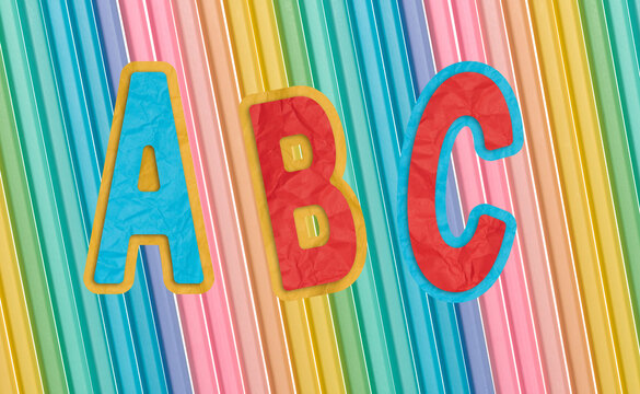 Volumetric paper letters A, B and C on a background of multi-colored vertical stripes.