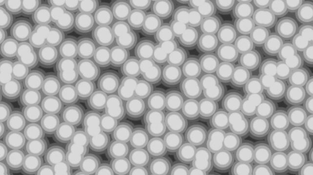A close-up view of numerous light grey, soft-edged circular shapes densely packed against a darker background, resembling cells or bubbles.