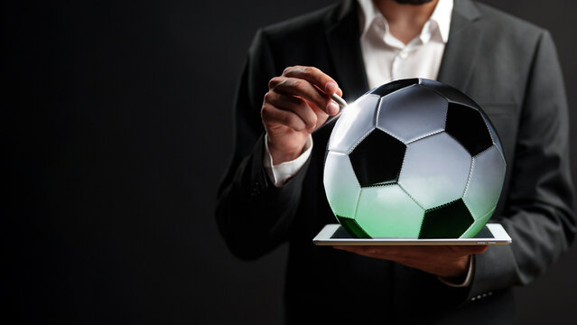 Betting on sports with a digital tablet showing a soccer ball in a black background setting