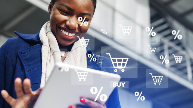 Woman shopping online and smiling while using a tablet in a bright, modern area with shopping symbols in the background