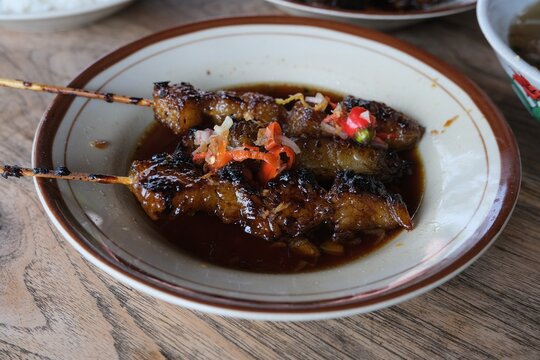 Close-up of iga bakar, a traditional Indonesian grilled ribs dish, served on a plate with rich dark sauce and fried garnish.