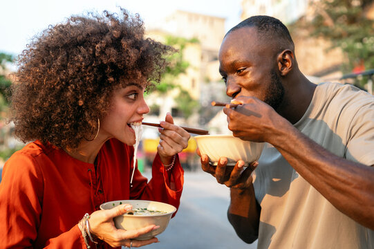 Diverse young friends enjoying street food together, sharing a happy, authentic multicultural moment