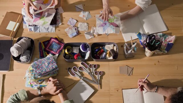 Top down shot of young adults participating in creative quilting workshop, sharing handmade patchwork blocks. Footage is perfect for promoting craft classes, community centers, or hobby supplies