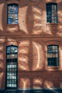 historic brick building facade with industrial loft windows and sunlight shadows, renovated urban brick architecture exterior with symmetrical windows and modern design details