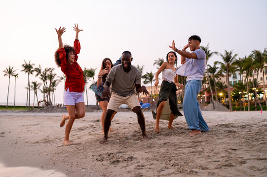 A diverse group of multicultural friends enjoying summer moments on the beach, dancing, laughing