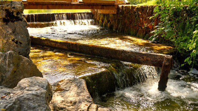 Small wooden dam and cascading clear water over mossy rocks in Triglav National Park, Slovenia.