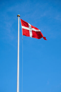Danish flag on a mast waving in the wind.