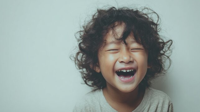 Joyful child with curly hair laughing heartily eyes closed