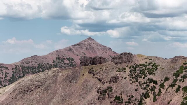 Aerial of high altitude peaks and scree slopes in Utah Uinta Mountains in summer with multiple prominent ridges under partly cloudy skies in Wasatch national Forest